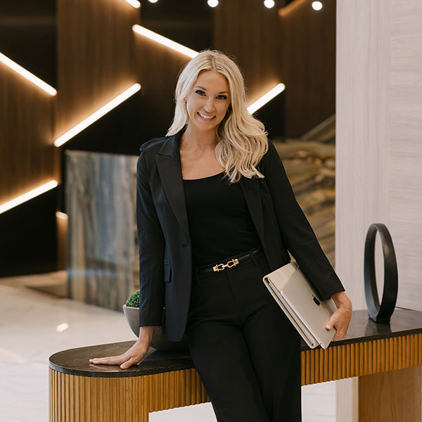 Kassidy Watkins poses in a black suit. She is smiling.
