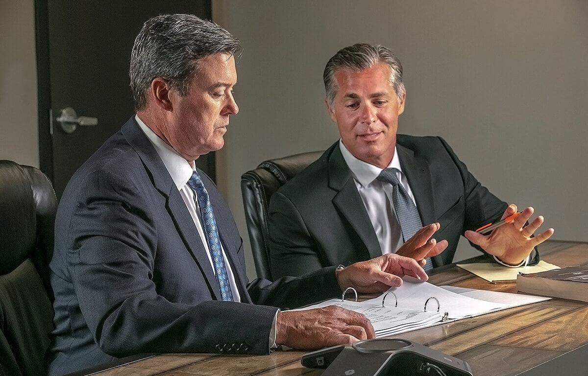 Paul Dugan, Jr and Dan Giroux sitting at a conference table reviewing notes.